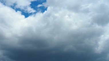 Mavi gökyüzüne karşı hızlı hareket eden bulutlar. Bulutlu kümülüs bulutları rüzgarda gittikçe daha alçaktan ve daha hızlı hareket eder. Meteoroloji ve hava tahmini. Ekolojik sorunlar. İklim değişikliği Fırtınanın hızı 4K