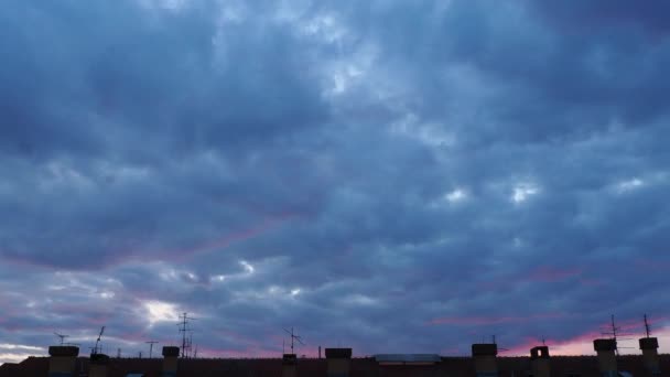 Roze - blauwe zonsondergang over het dak van de stad met antennes. Tijdsverloop, snelle video opname. Prachtige kleuren van de avondlucht en vliegende wolken. Roze reflecties van de ondergaande zon. Stof 4k — Stockvideo