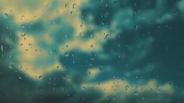 Bardaktan aşağı yağmur damlaları akıyor. Fırtınanın hızı azalıyor. Yumuşak odaklanma. Mavi gökyüzüne karşı hızlı hareket eden bulutlar. Bulutlu kümülüs bulutları rüzgarda gittikçe daha alçaktan ve daha hızlı hareket eder. Meteoroloji ve hava tahmini. 