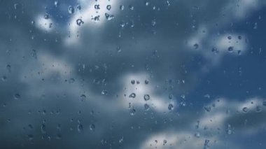 Bardaktan aşağı yağmur damlaları akıyor. Fırtınanın hızı azalıyor. Yumuşak odaklanma. Mavi gökyüzüne karşı hızlı hareket eden bulutlar. Bulutlu kümülüs bulutları rüzgarda gittikçe daha alçaktan ve daha hızlı hareket eder. Meteoroloji ve hava tahmini. 