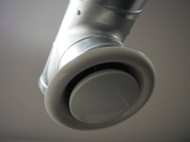 Umumi tuvalette çıkarıcı kaput. Gri hava çıkarıcılı yuvarlak metal boru. Mühendislik havalandırma sistemleri. Odanın tavanının altındaki galvanize borular. Plastik yuvarlak uç