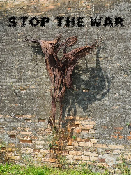 Stop the war. Anti-war inscription in black. Brick background. A call to peace. No war. Abstract silhouette of a man crucified on a wall, or burned in a nuclear explosion. Roots or bark of a tree. — Fotografia de Stock