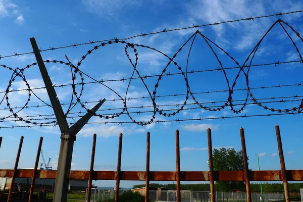 Barbed wire against the blue sky. Barbed wire is a wire or a narrow strip of metal with sharp spikes. Device of barriers. The concept of freedom, protection of property, violence, imprisonment.