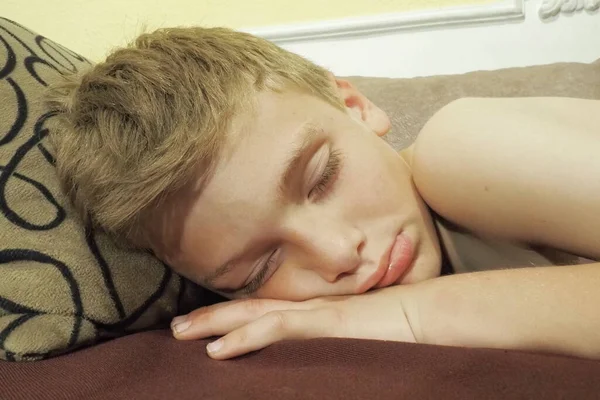 10 year old Caucasian boy fell asleep on the couch. Childrens dream. Sleep problems, falling asleep, insomnia, fatigue. The concept of health, mode of wakefulness and rest, education and prevention