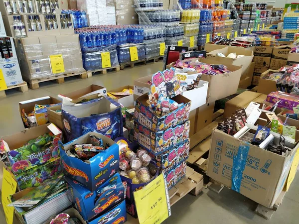 indirimli mağaza zinciri Mthe Ruma, Sırbistan, 15 Nisan 2022. Depoda düşük fiyattan yiyecek ve ev eşyaları satılıyor. Yiyecek ve içecek raflarda. Paletlerin üzerindeki kutular. Sarı fiyat etiketleri.