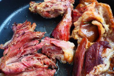 Roasted smoked pork shoulder or knee. Delicious meat on a black baking sheet with drops of vegetable oil, taken out of the oven. Pork delicacy for dinner in a restaurant and family lunch. Red meat.