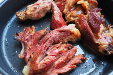 Roasted smoked pork shoulder or knee. Delicious meat on a black baking sheet with drops of vegetable oil, taken out of the oven. Pork delicacy for dinner in a restaurant and family lunch. Red meat.
