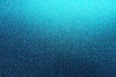 Deep blue. Texture of rough paper or cardboard. Defocused bokeh sparkles and shining. Festive blue background with illuminated gradient from top right. Deep blue sapphire