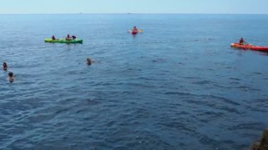 Dubrovnik, Hırvatistan, Buza plajı, Adriyatik Denizi, 14 Ağustos 2022. Bir grup turist dalgalarda çift kanoya biniyor. İnsanlar rahatlar ve deniz yolculuklarının tadını çıkarırlar. Kürekler küreklerle kürek çekiyor. İnsanlar yüzüyor..