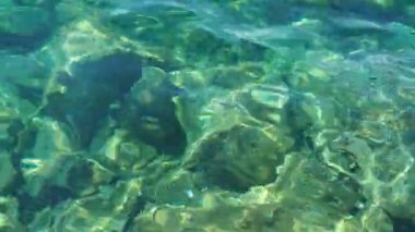 Yeşil mavi turkuaz şeffaf deniz tuzlu su dokusu. Su yüzeyinin üst görüntüsü ve dalgalanmalar. Su dalgaları arka planda. Alglerle kayalık taban kristal su yoluyla görülebilir..