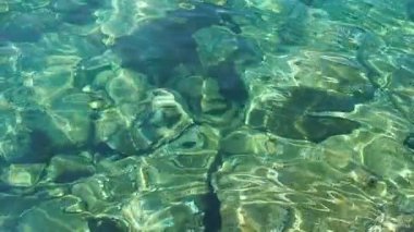Yeşil mavi turkuaz şeffaf deniz tuzlu su dokusu. Ağır çekim. Su yüzeyi ve dalgalar. Su dalgaları arka planda. Alglerle kayalık taban kristal su yoluyla görülebilir..