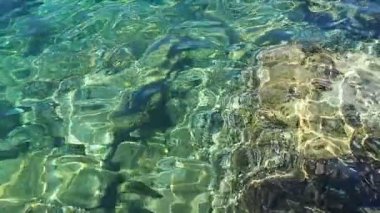 Yeşil mavi turkuaz şeffaf deniz tuzlu su dokusu. Ağır çekim. Su yüzeyi ve dalgalar. Su dalgaları arka planda. Alglerle kayalık taban kristal su yoluyla görülebilir..