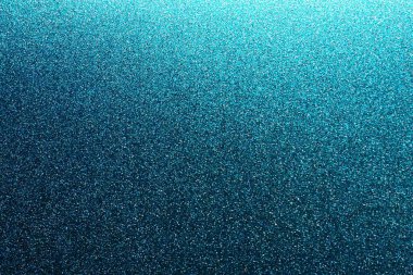 Deep blue. Texture of rough paper or cardboard. Defocused bokeh sparkles and shining. Festive blue background with illuminated gradient from top right. Deep blue sapphire