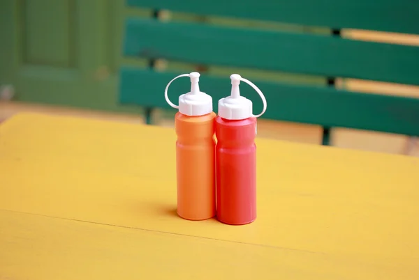 Bottiglia di salsa di peperoncino e pomodoro sul tavolo giallo — Foto Stock