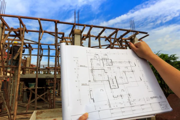 Architecture drawings in hand on house building background — Stock Photo, Image