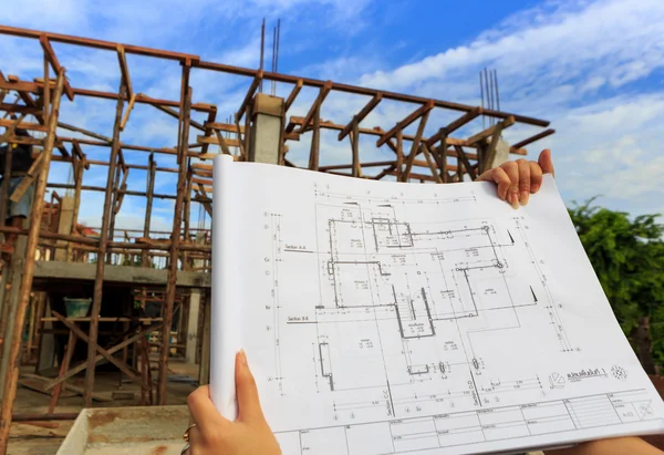 Architecture drawings in hand on house building background — Stock Photo, Image