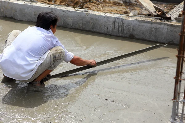 Un operaio in calcestruzzo intonaco al lavoro sul pavimento — Foto Stock