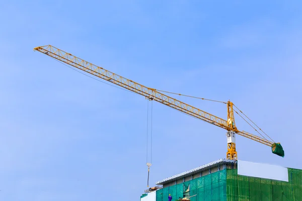 Jeřáb pracuje ve stavebnictví na modré obloze — Stock fotografie
