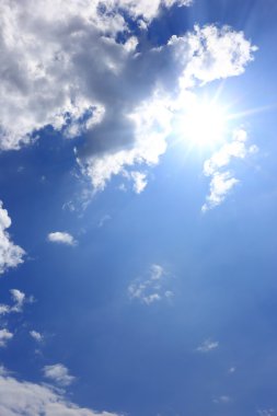 mavi gökyüzünde güneş ile bulutlar