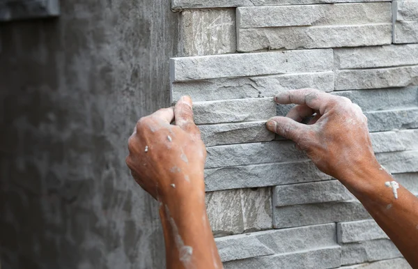 Arbeiter verlegen Steinmauer mit Zement für Haus Stockbild