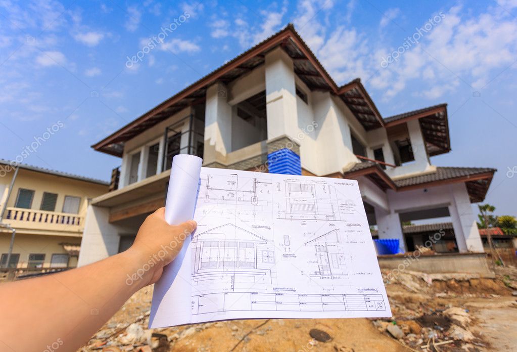 Architecture drawings in hand on big house building Stock Photo by