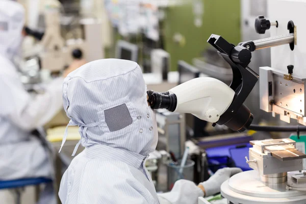 Operador em microscópio de uso de fábrica — Fotografia de Stock