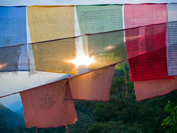 Untergehende Sonne, die durch bunte Gebetsfahnen mit dem Himalaya scheint — Stockfoto