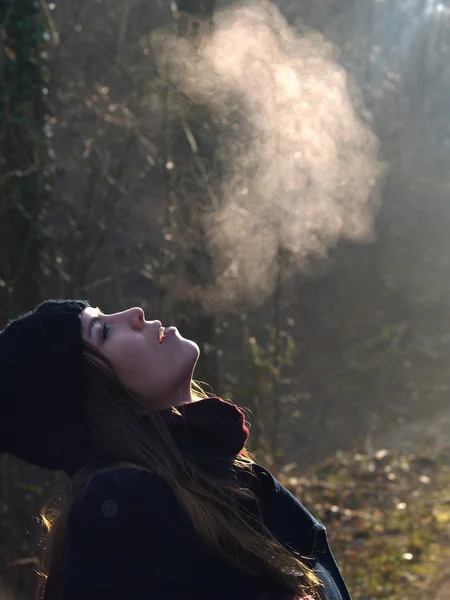 Mooi meisje warme lucht ademhaling tijdens een koude herfst ochtend — Stockfoto