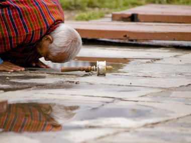 yaşlı bir adam ile bir dua tekerlek-onun önünde yere Buda'ya dua
