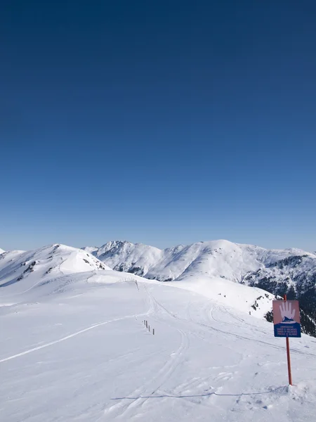 Um sinal nos alpes austríacos que diz perigo de avalanches — Fotografia de Stock