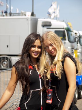 Two pitbabes are posing behind the pitlane clipart