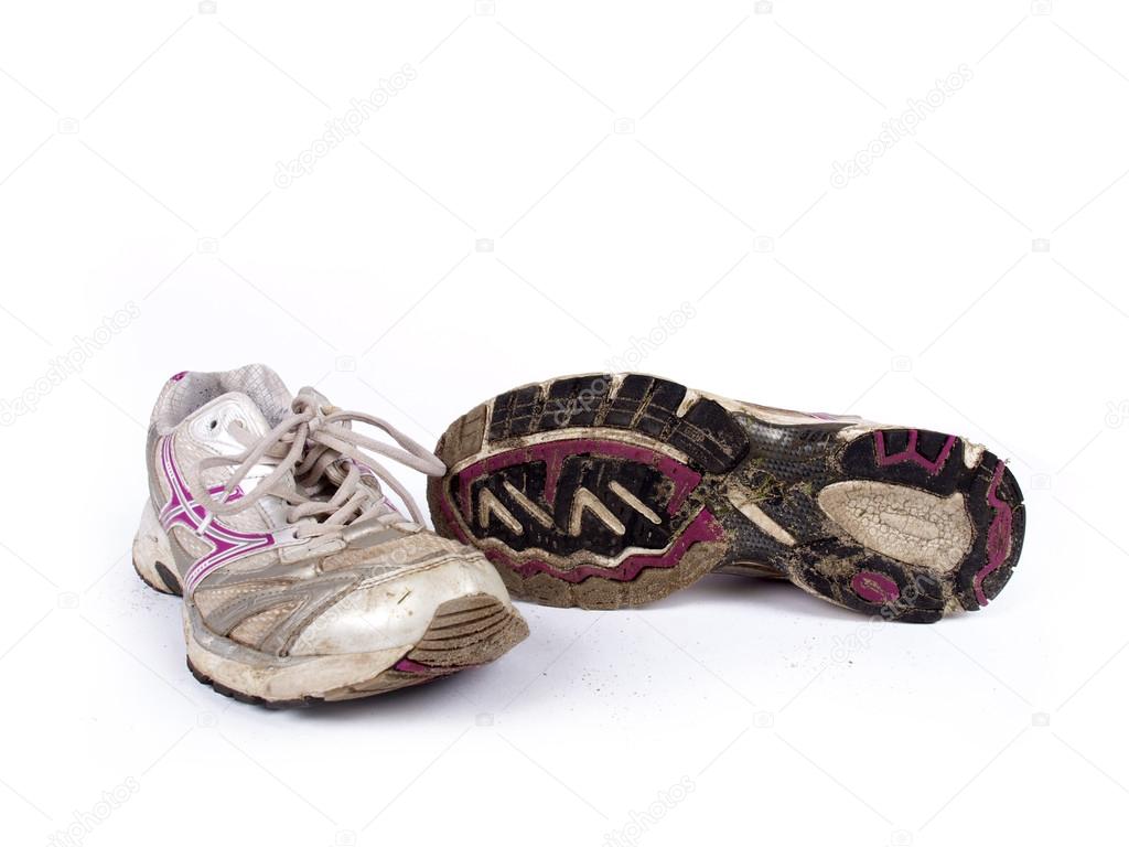Very old dirty pair of running shoes over a white background