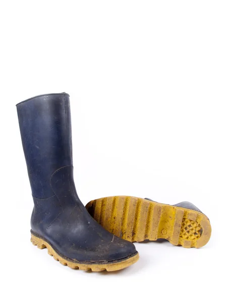 Paire de bottes en caoutchouc sale bleu foncé sur un fond blanc — Photo