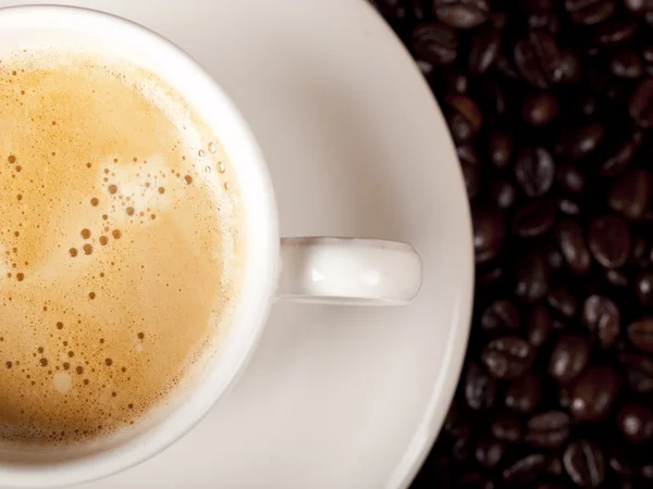 Top view of a cup of dark roasted coffee with coffeebeans — Stock Photo, Image