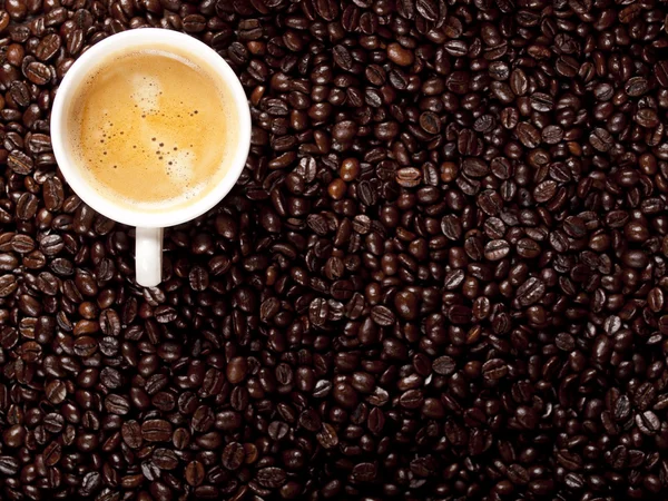 Top view of a cup of dark roasted coffee with coffeebeans — Stock Photo, Image