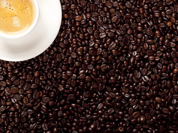 Top view of a cup of dark roasted coffee with coffeebeans — Stock Photo, Image