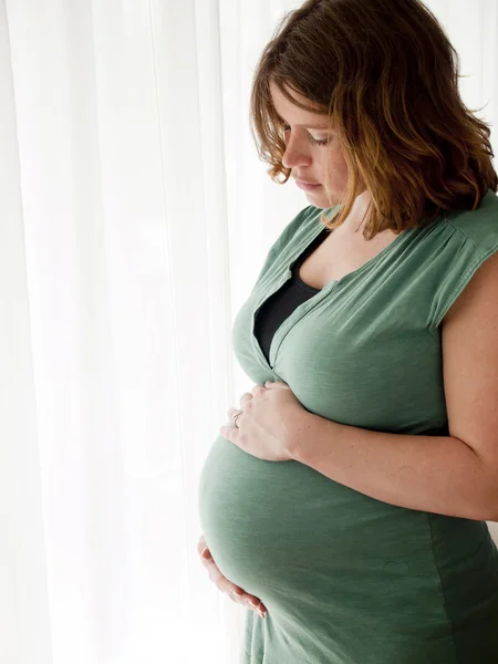 Pregnant young woman looking at her belly — Stock Photo, Image