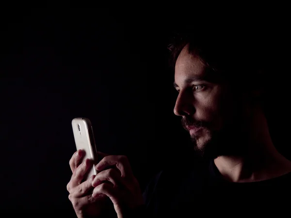 Low key image of a bearded man with a cellphone — Stock Photo, Image