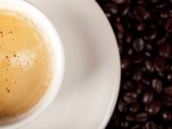 Top view of a cup of dark roasted coffee with coffeebeans — Stock Photo, Image