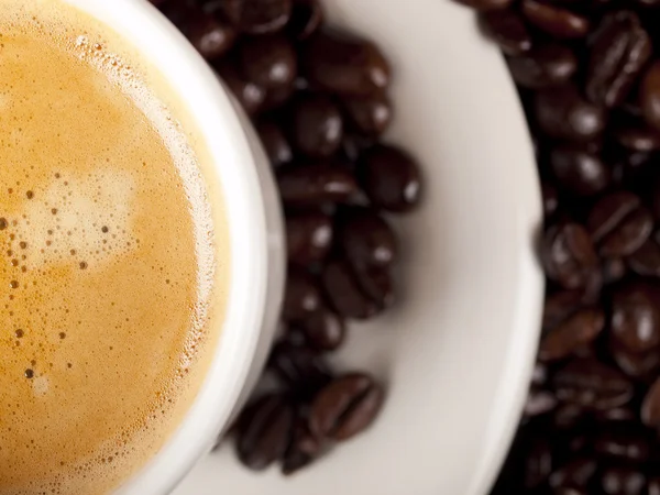 Top view of a cup of dark roasted coffee with coffeebeans — Stock Photo, Image