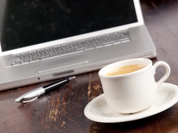 Laptop moderno com uma xícara de café ao lado dele — Fotografia de Stock