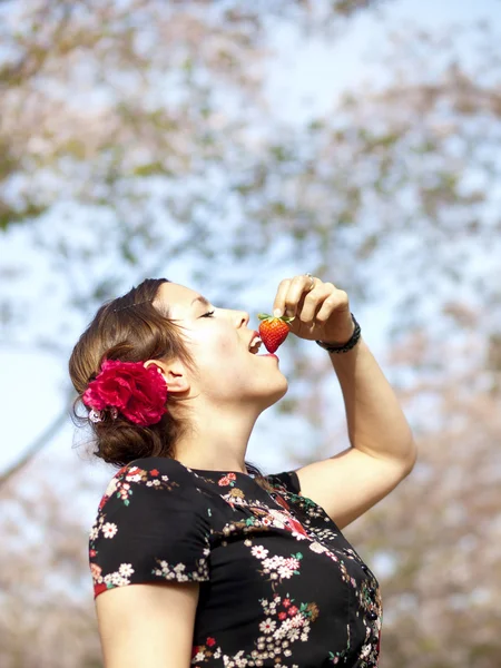Mooi meisje eten van een aardbei tijdens een picknick in het voorjaar — Stockfoto