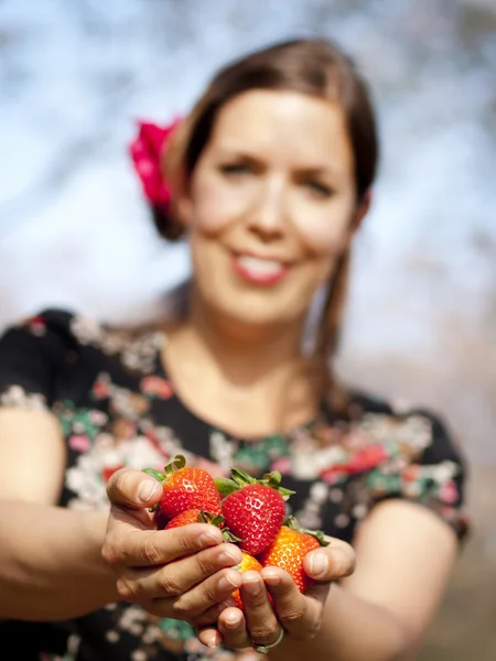 Beautiful girl is giving you strawberries during a sunny day — Stock Photo, Image