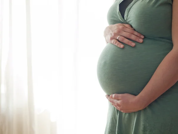 Schwangere junge Frau hält ihren Bauch — Stockfoto