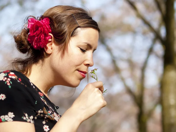 Hermosa chica oliendo una flor de cuco en la primavera Imagen de archivo