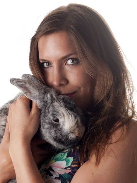 Улыбающаяся красивая брюнетка держит и гладит своего кролика — стоковое фото