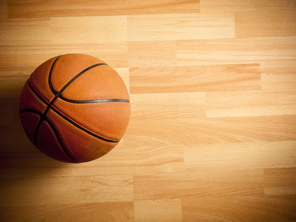 Een officiële oranje bal op een hardhouten basketbalveld — Stockfoto