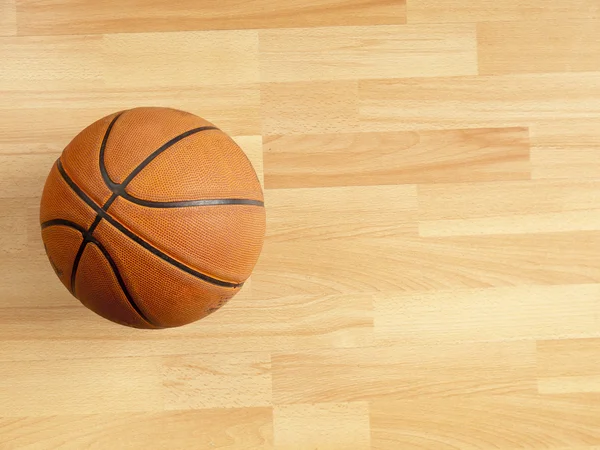 Uma bola laranja oficial em um campo de basquete de madeira dura — Fotografia de Stock