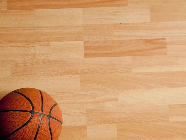 Uma bola laranja oficial em um campo de basquete de madeira dura — Fotografia de Stock