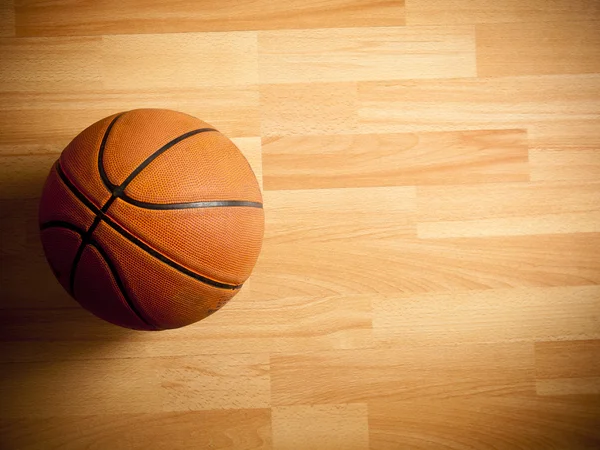 Una pelota naranja oficial en una cancha de baloncesto de madera dura Fotos de stock libres de derechos